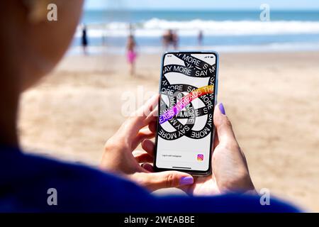 Consente di eseguire il thread dell'apertura dell'app in una schermata dello smartphone. Donna in spiaggia con un telefono cellulare in mano. Applicazione di conversazione basata su testo. Social network Foto Stock