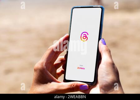 Consente di eseguire il thread dell'apertura dell'app in una schermata dello smartphone. Donna in spiaggia con un telefono cellulare in mano. Applicazione di conversazione basata su testo. Social network Foto Stock