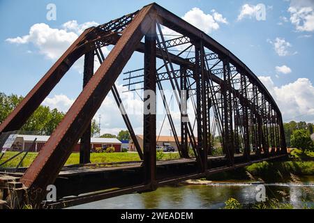 Rustic Truss Bridge sul fiume con sfondo industriale Foto Stock