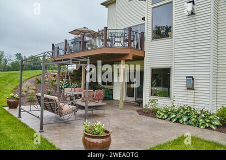 Moderno cortile suburbano con terrazza, sedile girevole e giardino paesaggistico Foto Stock