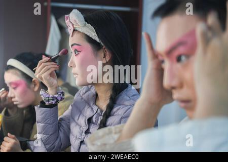 WUHAN, 24 gennaio 2024 (Xinhua) -- un'attrice (C) della Hanju Opera mette sul trucco a Wuhan, nella provincia di Hubei della Cina centrale, 23 gennaio 2024. Dal 2016, al fine di riservare talenti per le opere, l'Hubei Drama Art Theatre ha selezionato e reclutato più di 150 studenti di Chuju Opera, Hanju Opera e Huangmei Opera, e ha affidato l'Hubei College of the Arts per la formazione direzionale. Dopo sette anni di studio dell'opera e un anno di stage, questo gruppo di giovani attori operistici salì sul palco del gala di laurea con le loro migliori rappresentazioni. (Xinhua/Du Zixuan) Foto Stock