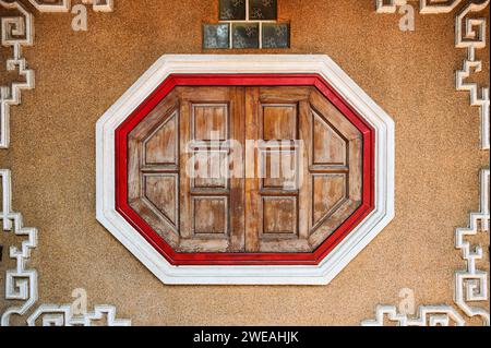 Antica finestra orientale in legno su un muro di pietra cinese Foto Stock