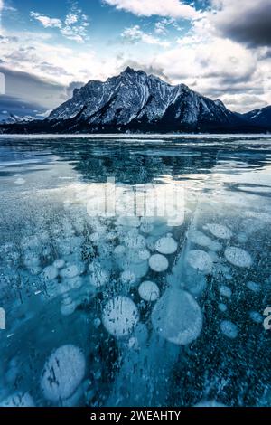 Fantastico paesaggio del ghiacciato lago Abraham, con montagne rocciose e bolle naturali che gelano la mattina d'inverno nella zona di Kootenay Plains, Alberta, C. Foto Stock