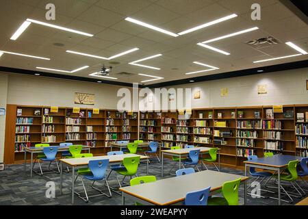 Moderno interno della biblioteca con sedie colorate e scaffali organizzati Foto Stock