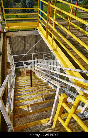 Scala industriale vibrante con rotaie gialle e gradini in metallo, vista discendente Foto Stock