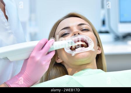 Dentista donna che utilizza uno scanner intraorale durante l'esame dei denti del paziente in una clinica odontoiatrica. Scansione intraorale con il concetto di moderno dispositivo di scansione. Foto Stock