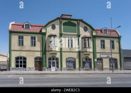 Paesaggio urbano con pittoresco edificio commerciale decorato in stile antico nella città storica , girato con una luce brillante di tarda primavera a Luderitz, Namibia, Africa Foto Stock