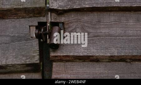 Blocco in metallo appeso a un cancello di legno. Un castello di metallo scuro in primo piano in un cancello fatto di tavole di legno. Foto Stock