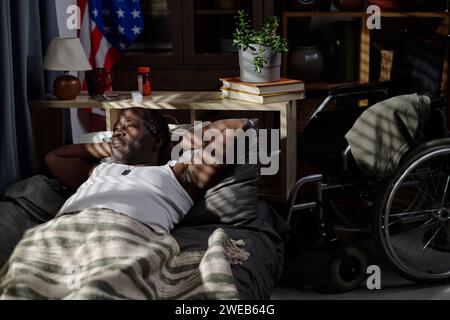 Un uomo afroamericano maturo, sdraiato da solo nel suo letto di notte e con un occhio attento alla finestra Foto Stock