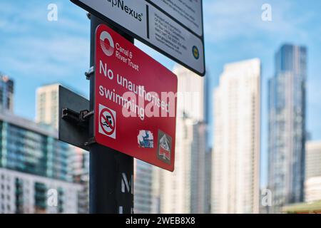 Nessun cartello per il nuoto non autorizzato, con Canary Wharf sullo sfondo. Molo interno Millwall, South Quay, Canary Wharf, Londra Foto Stock