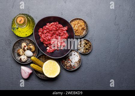 Cottura di una saporita tartare di manzo con cetriolini sottaceto e pane tostato. Base piatta con spazio per la copia Foto Stock