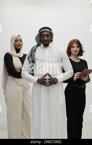 Un uomo d'affari arabo si affianca con fiducia a due donne d'affari, rappresentando un team pronto e diversificato che incarna ambizione, innovazione e Foto Stock