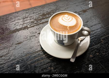 Tazza di caffè bianco piatto con latte art su un tavolo in legno rustico. Copia spazio. Foto Stock