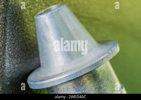 Primo piano dell'ugello in metallo flangiato a forma di triangolo del tubo dell'aria su sfondo verde grigiastro sfocato Foto Stock