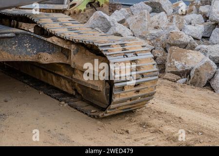 Montaggio su cingoli del retroescavatore davanti a pezzi di grandi dimensioni se il calcestruzzo è in cantiere Foto Stock