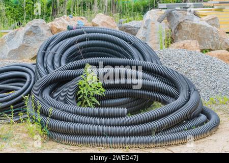 Tubo flessibile nero avvolto e steso a terra in cantiere Foto Stock