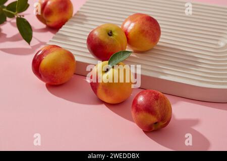 Vista ravvicinata delle pesche fresche decorate su un podio con foglie verdi. La pesca (Prunus persica) ha molti benefici per la pelle a causa della loro r Foto Stock