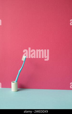 Spazzolino da denti nel supporto sul ripiano blu. sfondo a parete rosa Foto Stock