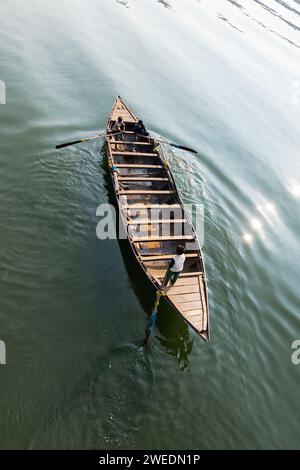 Vista dall'alto di una barca di legno che canoa sull'acqua verde da parte di un gruppo di bambini in India Foto Stock