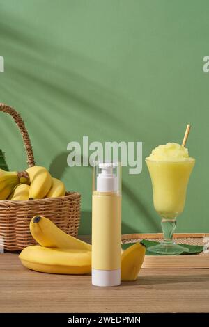 Una bottiglia a pompa senza marchio su un tavolo di legno con banane fresche e tazza per frullati. Scena di mockup per pubblicizzare cosmetici di estratto di banane. Le banane hanno ma Foto Stock