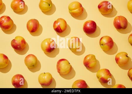 Colorato motivo di frutta di pesche fresche (prunus persica) su sfondo giallo. Background creativo per pubblicità e branding per cosmetici o prodotti Foto Stock