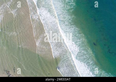 Un colpo aereo delle schiumose onde dell'oceano che colpiscono la spiaggia sabbiosa Foto Stock