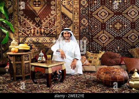Uomo degli emirati che indossa un abito kandura trascorre del tempo in una casa tradizionale araba a Dubai Foto Stock