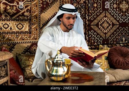 Uomo degli emirati che indossa un abito kandura trascorre del tempo in una casa tradizionale araba a Dubai Foto Stock