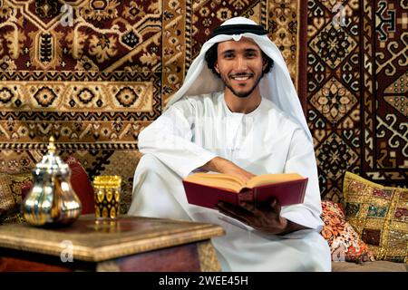 Uomo degli emirati che indossa un abito kandura trascorre del tempo in una casa tradizionale araba a Dubai Foto Stock