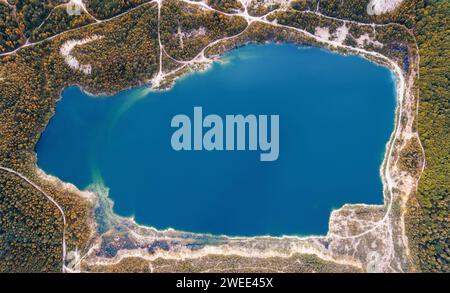 Lago di smeraldo in una cava allagata nella foresta da una vista a volo d'uccello. Fotografia con droni. Foto Stock