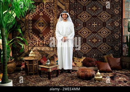 Uomo degli emirati che indossa un abito kandura trascorre del tempo in una casa tradizionale araba a Dubai Foto Stock