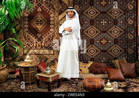 Uomo degli emirati che indossa un abito kandura trascorre del tempo in una casa tradizionale araba a Dubai Foto Stock