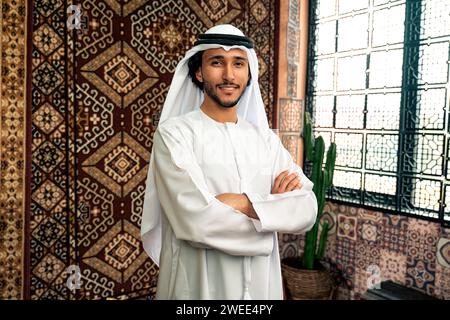 Uomo degli emirati che indossa un abito kandura trascorre del tempo in una casa tradizionale araba a Dubai Foto Stock