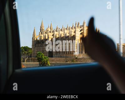 Una foto che mostra un'ampia vista di un grande edificio della cattedrale di Maiorca a Palma di Maiorca, Spagna, scattata dalla prospettiva all'interno di un veicolo, puntando con il dito Foto Stock