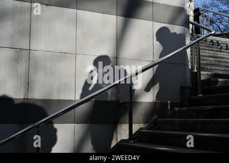 Ombre sul muro di due uomini che scendono per i gradini di un passaggio Foto Stock