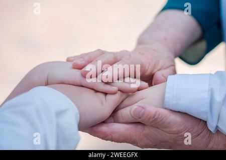 Una donna anziana tiene le mani dei bambini nei palmi. Foto Stock