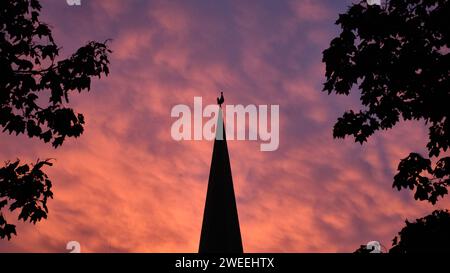 Brunswick, Germania. 2 novembre 2023. Le nuvole si tingono di rosa dalla luce del sole nascente, con il campanile di San La Chiesa evangelica luterana di Peter e il suo rubinetto antistante. Crediti: Stefan Jaitner/dpa/Alamy Live News Foto Stock