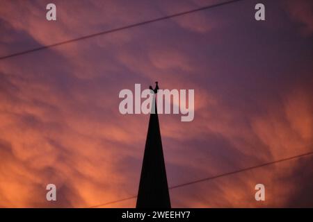 Brunswick, Germania. 2 novembre 2023. Le nuvole si tingono di rosa dalla luce del sole nascente, con il campanile di San La Chiesa evangelica luterana di Peter e il suo rubinetto antistante. Crediti: Stefan Jaitner/dpa/Alamy Live News Foto Stock