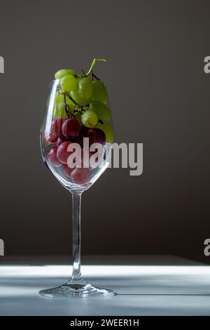 bicchiere di vino ripieno di uva verde e rossa Foto Stock
