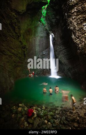 Kobarid, Slovenia - 28 giugno 2010: Alcuni giovani turisti nuotano e si divertono nel torrente alpino e nel lago sotto la cascata Kozjak. Foto Stock