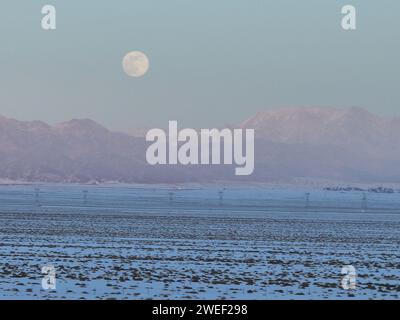 HAMI, CINA - 25 GENNAIO 2024 - Una luna luminosa sorge sui monti Tianshan orientali a Hami, provincia dello Xinjiang, Cina, 25 gennaio 2024. Il primo pieno Foto Stock