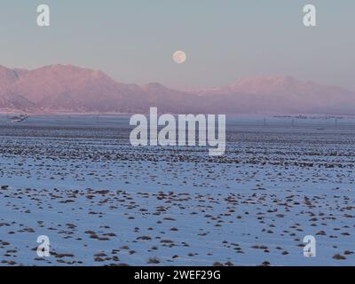 HAMI, CINA - 25 GENNAIO 2024 - Una luna luminosa sorge sui monti Tianshan orientali a Hami, provincia dello Xinjiang, Cina, 25 gennaio 2024. Il primo pieno Foto Stock