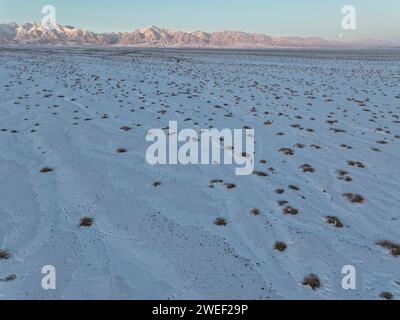 HAMI, CINA - 25 GENNAIO 2024 - Una luna luminosa sorge sui monti Tianshan orientali a Hami, provincia dello Xinjiang, Cina, 25 gennaio 2024. Il primo pieno Foto Stock