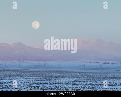 HAMI, CINA - 25 GENNAIO 2024 - Una luna luminosa sorge sui monti Tianshan orientali a Hami, provincia dello Xinjiang, Cina, 25 gennaio 2024. Il primo pieno Foto Stock