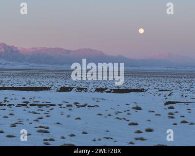 HAMI, CINA - 25 GENNAIO 2024 - Una luna luminosa sorge sui monti Tianshan orientali a Hami, provincia dello Xinjiang, Cina, 25 gennaio 2024. Il primo pieno Foto Stock