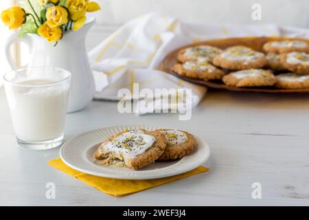 Biscotti keto al limone con semi di pappe serviti con latte e un vassoio di altri ingredienti dietro di te. Foto Stock