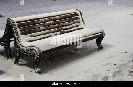 Panchine cittadine in inverno coperte di neve Foto Stock