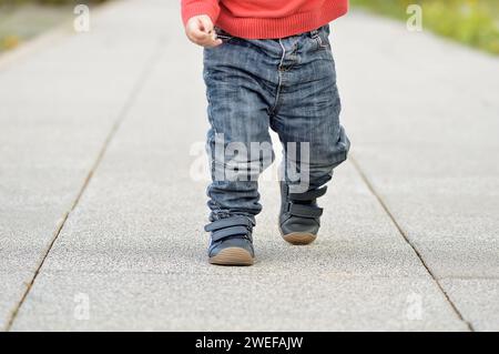 Immagine ritagliata delle gambe di un bambino che cammina per strada Foto Stock