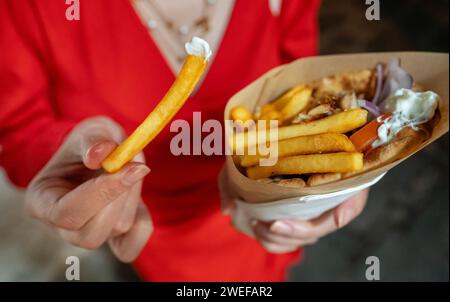 Donna mangia pita con patatine fritte. Foto Stock