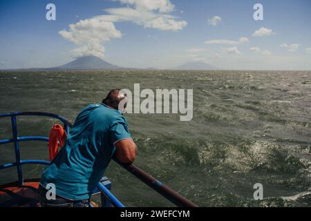 Un uomo su una barca che guarda i vulcani lontani Foto Stock